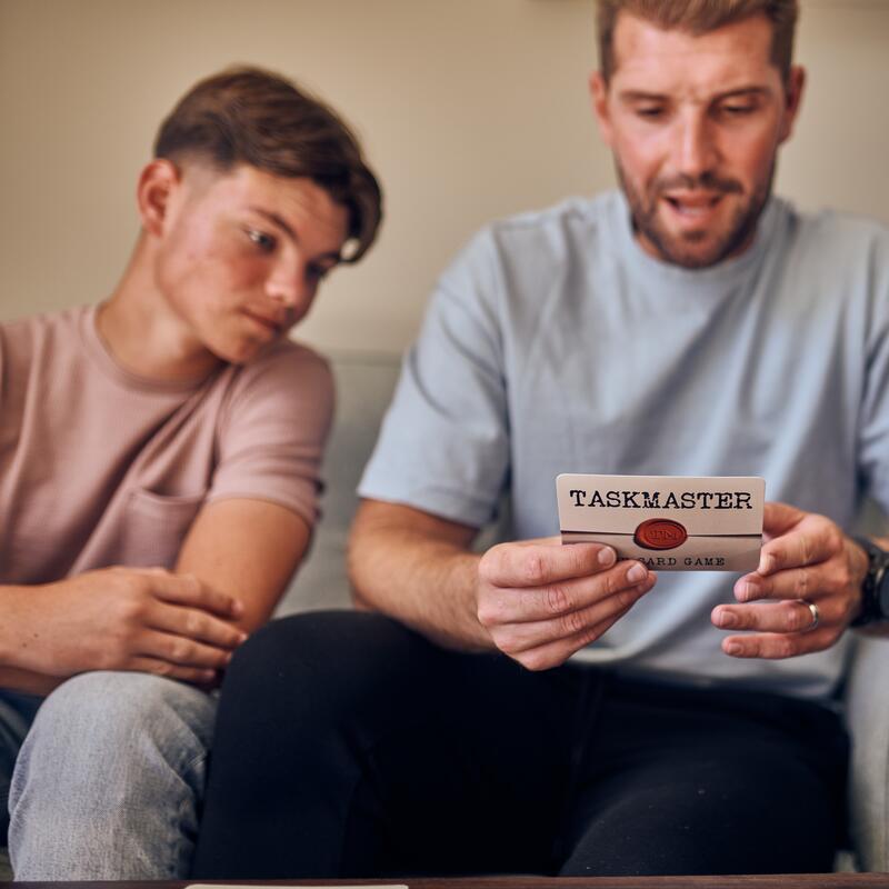 Taskmaster card game lifestyle image of father and son reading task card