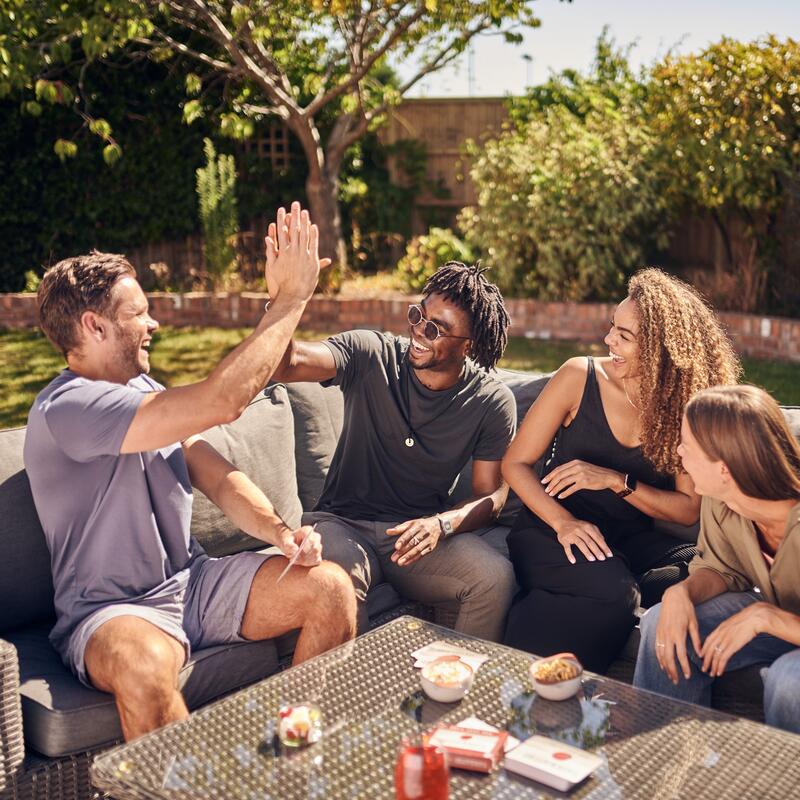 Taskmaster card game lifestyle image of friends high-fiving playing game outside
