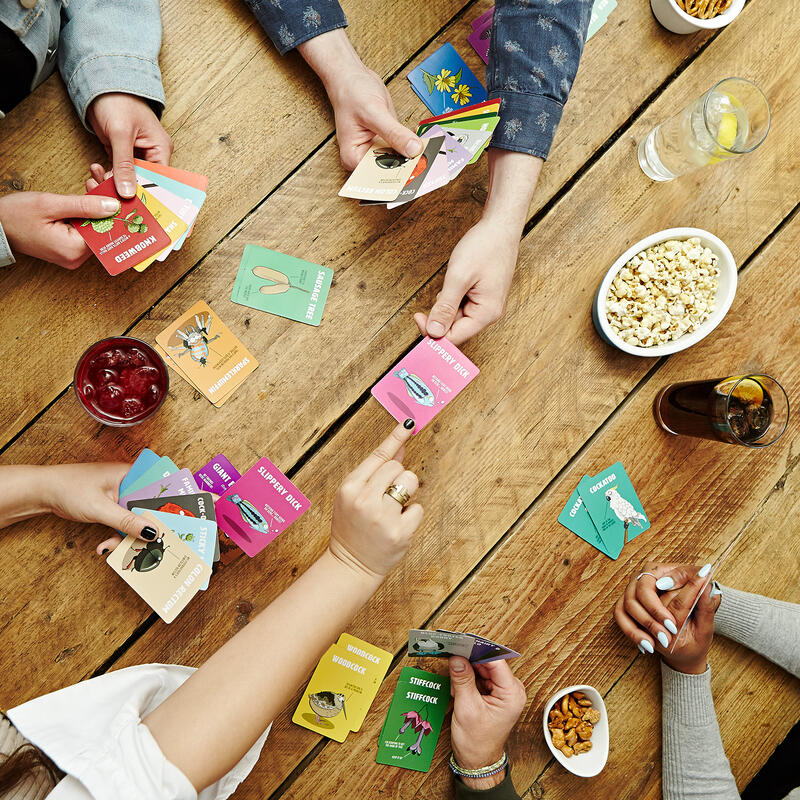 Players hands passing a Dont Be A Dik Dik card across the table