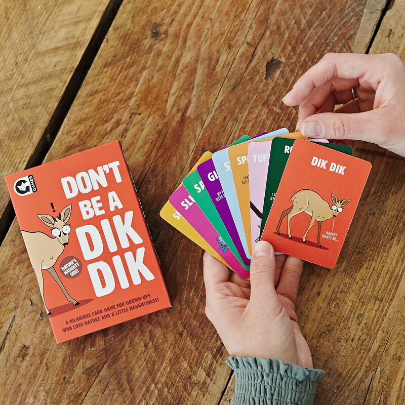 Close up of a person holding a set of Dont Be A Dik Dik cards with the box next to them